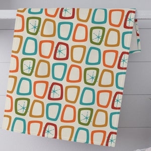May include: A kitchen towel with a retro pattern of colorful, rounded squares and starbursts on a cream background.