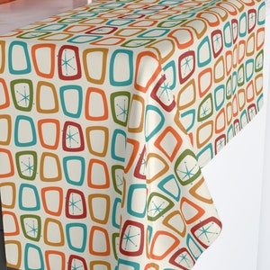 May include: A white table runner with a retro mid-century modern design featuring a repeating pattern of colorful squares and starbursts.