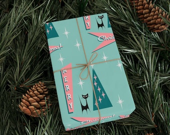 May include: A wrapped gift with a retro Christmas design. The wrapping paper is teal with pink and black accents, featuring stylized Christmas trees, stars, and the words "Merry Christmas." The gift is tied with twine and set on a bed of pine needles.