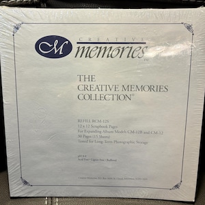 May include: A sealed package of Creative Memories scrapbook refill pages. The package is white with a blue border and features the Creative Memories logo and text. The text includes "THE CREATIVE MEMORIES COLLECTION" and "REFILL RCM-12S".