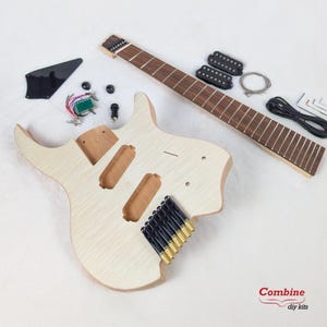 May include: Unfinished electric guitar kit with a light wood body, a separate fretboard, and various black and gold hardware components. Includes pickups, a tremolo bridge, and wiring. Designed for DIY guitar building.