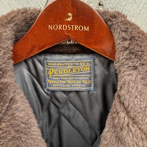 May include: Close-up of a brown Pendleton wool coat with a dark quilted lining. The coat is on a wooden Nordstrom hanger. A blue and gold Pendleton label is visible, along with the Nordstrom logo.