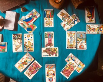 Könnte beinhalten: Eine Tarotkarten-Auslage auf einem blauen Tischtuch. Die Karten sind in einem Kreis angeordnet, wobei die "Turm"-Karte in der Mitte liegt. Die Karten sind alle in verschiedenen Farben und haben verschiedene Bilder.