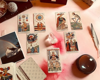 Könnte beinhalten: Eine Tarotkarten-Auslage auf einer rosa Oberfläche mit einem Kristall, einer Feder und einer Lupe. Die Karten stammen aus dem Rider-Waite-Tarot-Deck und beinhalten Der Stern, Die Sonne, Stärke, Tod, Das Gericht, Der Wagen und Die Liebenden.
