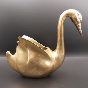 May include: A gold swan-shaped decorative bowl. The swan has a long neck and a detailed head with a beak.