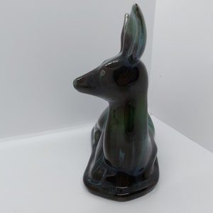 May include: A ceramic figurine of a black and green deer sitting down. The deer has a glossy finish and is a decorative piece.