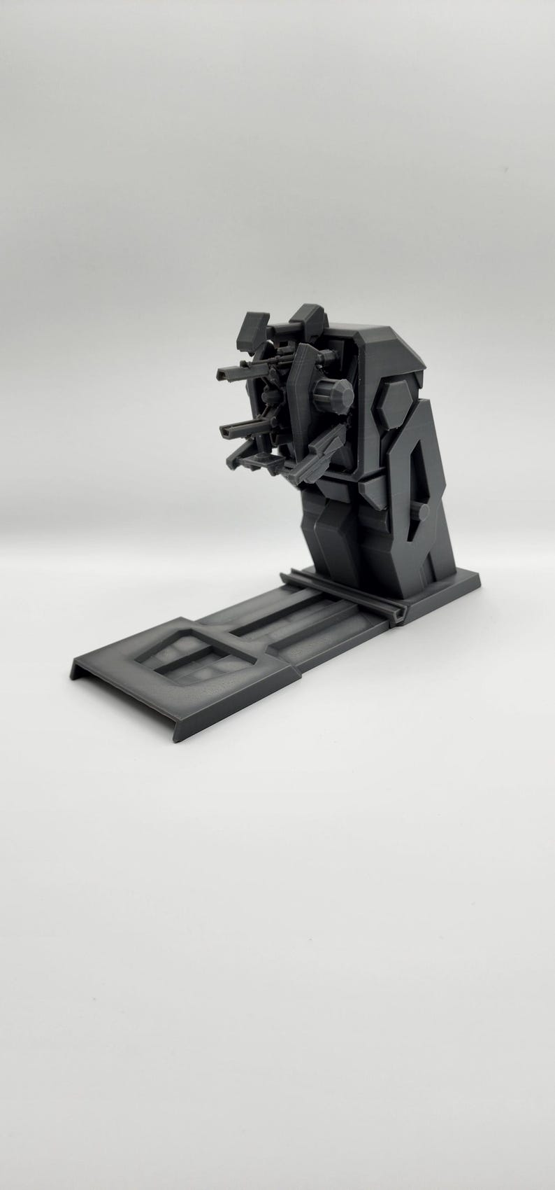 Puede incluir: Un modelo de pl&aacute;stico negro de una torreta de armas futurista con un ca&ntilde;&oacute;n giratorio y varios ca&ntilde;ones. La torreta est&aacute; montada sobre una base de pl&aacute;stico negro.