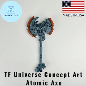 May include: A gray and orange Atomic Axe, a TF Universe Concept Art design. The axe features a detailed, mechanical design with a long handle and a double-bladed head. The image also includes the text "Made in USA".