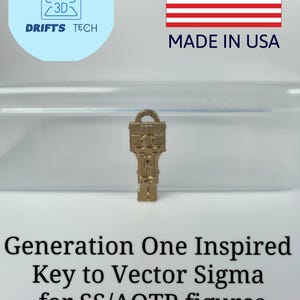 May include: A gold-coloured key with an intricate design, standing upright. The key is labelled "Generation One Inspired Key to Vector Sigma for SS/AOTP figures." The image also includes the text "MADE IN USA" and a logo for "Drifts Tech."