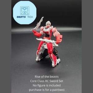 Może przedstawiać: Czerwono-biała zabawka robot z dwoma srebrnymi mieczami. Zabawka pochodzi z linii Transformers Rise of the Beasts. Tekst "Core Class RC Sword Set" jest nadrukowany pod zabawką. Tekst "No figure is included" jest nadrukowany pod zabawką. Tekst "purchase is for a pair(two)" jest nadrukowany pod zabawką.