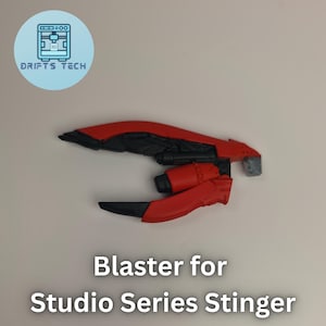 May include: A red and black blaster toy for the Studio Series Stinger, with a futuristic design. The image includes the text "Blaster for Studio Series Stinger" and a logo for Drifts Tech.