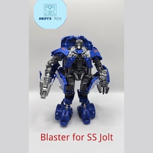 May include: A blue and silver Transformers action figure holding a blaster. The figure is posed in a standing position with its arms outstretched. The text "Blaster for SS Jolt" is printed below the figure.