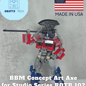 May include: A red, silver, and blue action figure of a robot holding a weapon. The figure is labeled "BBM Concept Art Axe for Studio Series ROTB 102." The image also includes a "Made in USA" graphic and a logo for "Drifts Tech."