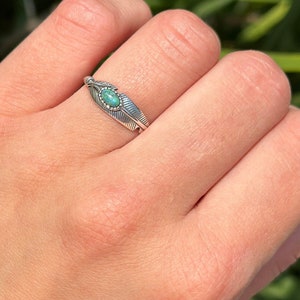 May include: A silver ring with a turquoise stone set in a feather design.