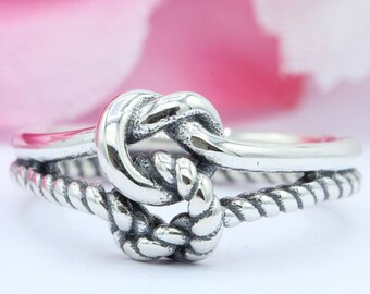 May include: A silver ring with a knot design. The knot is made of a twisted rope design and is set on a plain band.