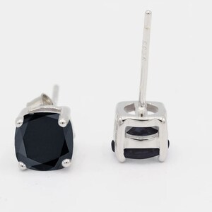 May include: A pair of silver stud earrings with black square-shaped gemstones.