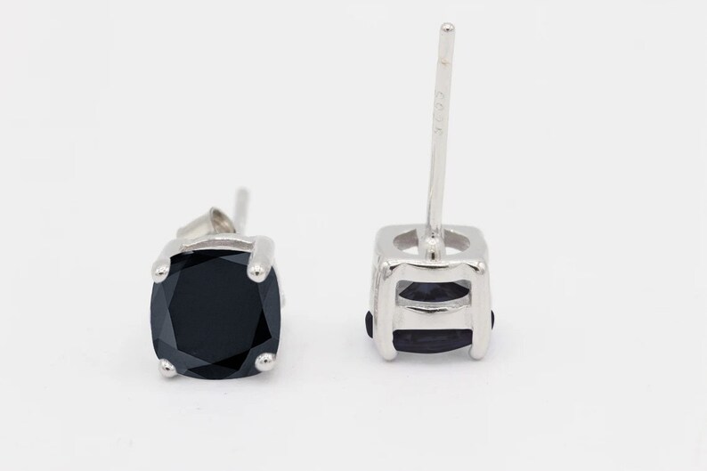 May include: A pair of silver stud earrings with black square-shaped gemstones.