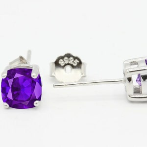 May include: A pair of silver stud earrings with a square purple amethyst gemstone. The earrings have a post and butterfly back.