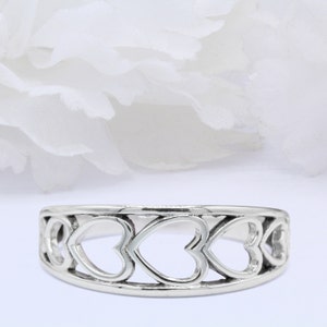 May include: A silver ring featuring a design of five interlocked hearts.