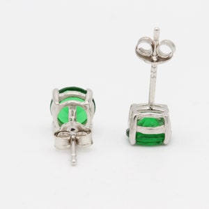 May include: A pair of silver stud earrings with green gemstones. The earrings have a simple design and are perfect for everyday wear.