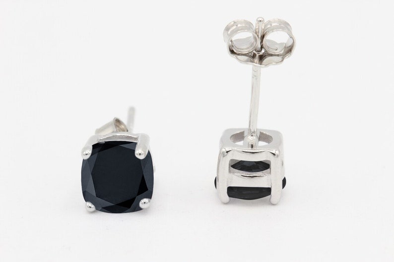 May include: A pair of silver stud earrings with black square-shaped gemstones.