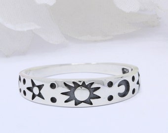 May include: A silver ring with a sun, moon, and star design. The ring is a simple band with the celestial symbols etched into the surface.