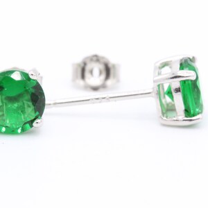 May include: A pair of silver stud earrings with green gemstones.