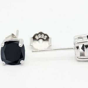 May include: A pair of silver stud earrings with black square-shaped gemstones. The earrings have a post and butterfly back.