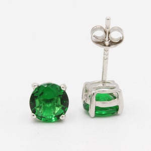 May include: A pair of silver stud earrings with round green gemstones.