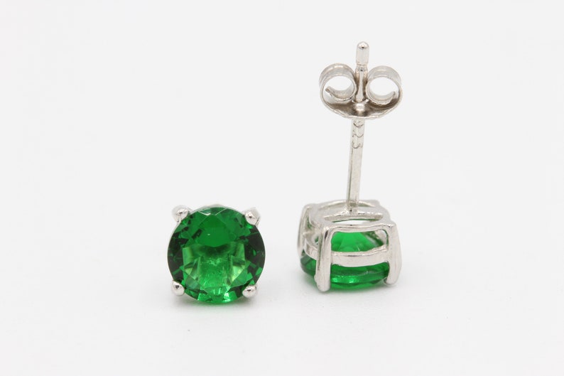 May include: A pair of silver stud earrings with round green gemstones.