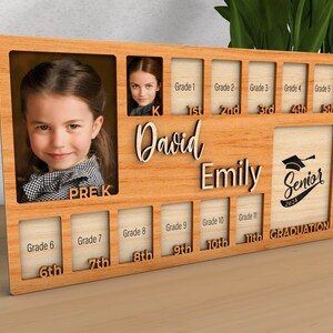 Pode incluir: Um quadro de fotos de madeira com espa&ccedil;os para fotos de cada ano escolar, desde o pr&eacute;-K at&eacute; a gradua&ccedil;&atilde;o. O quadro tem os nomes "David" e "Emily" escritos nele, e as palavras "Senior 2024" est&atilde;o em forma de um chap&eacute;u de formatura.