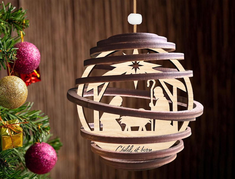 Puede incluir: Un adorno navide&ntilde;o de madera con un dise&ntilde;o en capas que representa la escena de la natividad. El adorno es marr&oacute;n y presenta una estrella, un pesebre y el texto "Child is born".