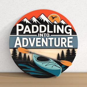 May include: A round wooden sign with the words "Paddling Into Adventure" in white. The sign features a mountain range, a kayak, and a paddle. The color scheme includes orange, blue, black, and white.