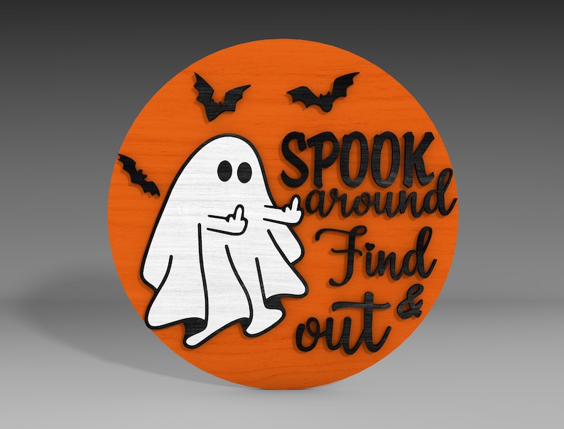 Op de afbeelding: Een rond, oranje houten bord met een witte geest die de middelvinger opsteekt. Het bord zegt "Spook around Find out &" in zwarte letters. Er zijn drie zwarte vleermuizen op het bord.
