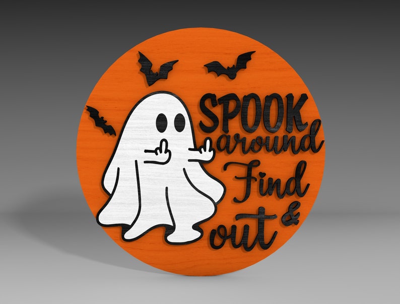 Op de afbeelding: Een rond, oranje houten bord met een witte geest die de middelvinger opsteekt. Het bord zegt "Spook around Find out &" in zwarte letters.