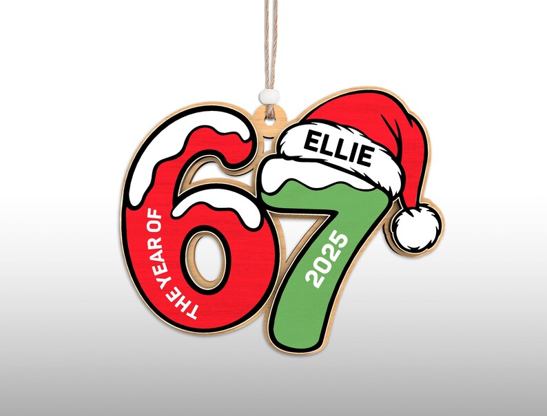 May include: Wooden Christmas ornament in the shape of the number 67, with the text "THE YEAR OF" on the 6 and "2025" on the 7. The 7 is green and topped with a red Santa hat with the name "ELLIE".