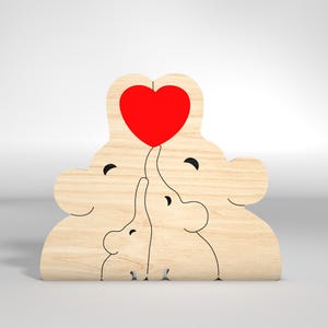 May include: Wooden cutout of three elephants, two larger elephants with a red heart between them, and a smaller elephant in the middle. The elephants are all facing forward and have simple, cartoon-like features.