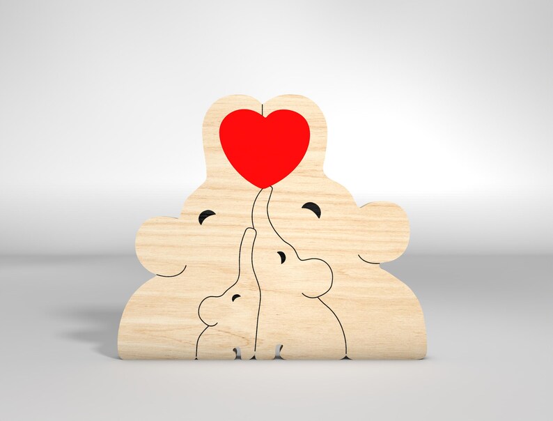 May include: Wooden cutout of three elephants, two larger elephants with a red heart between them, and a smaller elephant in the middle. The elephants are all facing forward and have simple, cartoon-like features.
