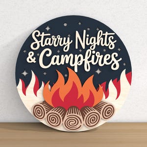 May include: A round wooden sign with the words "Starry Nights & Campfires" in white script. The sign features a campfire design with flames in red, orange, and white, and logs at the base. The background is dark blue with star cutouts.