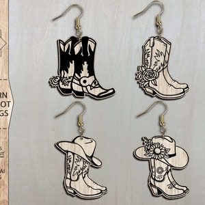 May include: Four pairs of laser cut wooden earrings featuring a western cowgirl boot design. Two pairs feature a boot with a flower design and two pairs feature a boot with a cowboy hat.