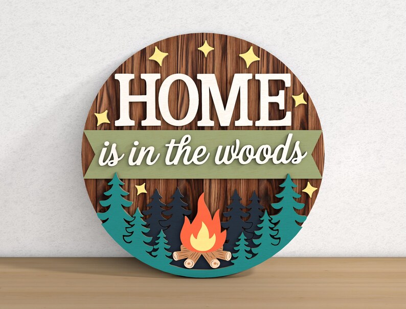 May include: A round wooden sign with the text "HOME is in the woods". The sign features a wood grain background, white lettering, and a forest scene with a campfire. Yellow star accents are also included.