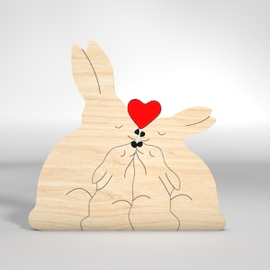 May include: A wooden cutout of two rabbits kissing with a red heart above them.