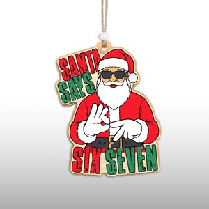 May include: Wooden Christmas ornament featuring Santa Claus wearing sunglasses and a red suit. The ornament reads "SANTA SAYS SIX SEVEN" in red and green lettering. The ornament is hanging by a string.