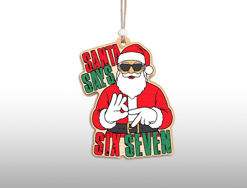 May include: Wooden Christmas ornament featuring Santa Claus wearing sunglasses and a red suit. The ornament reads "SANTA SAYS SIX SEVEN" in red and green lettering. The ornament is hanging by a string.