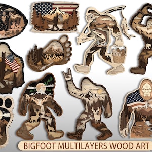 Op de afbeelding: Een collectie van gelaagde houten kunstwerken met Bigfoot-silhouetten, berglandschappen, bossen, herten en Amerikaanse vlaggen. Sommige ontwerpen bevatten de tekst Believe en Bigfoot Multilayers Wood Art. De stukken zijn vervaardigd in diverse vormen, waaronder voetafdrukken en volledige figuren.