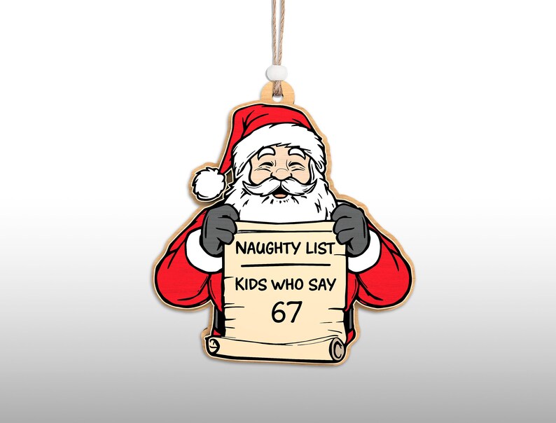 May include: Wooden Christmas ornament featuring Santa Claus holding a scroll. Santa is dressed in a red suit and hat with a white beard. The scroll reads "NAUGHTY LIST KIDS WHO SAY 67". The ornament has a string for hanging.