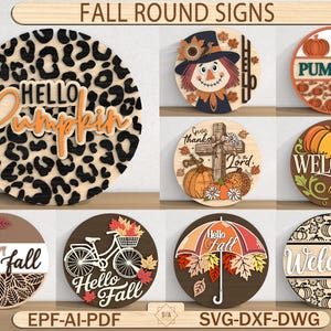 Könnte beinhalten: Eine Sammlung runder Holzschilder mit herbstlichen Designs. Die Schilder zeigen Kürbisse, Vogelscheuchen und Herbstblätter. Einige Schilder haben Texte wie "Hello Pumpkin" und "Welcome". Geeignet für saisonale Heimdekoration.
