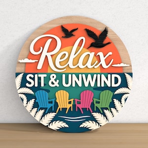 May include: A round wooden sign with the words "Relax SIT & UNWIND" in white script. The sign features a sunset, birds, and colorful Adirondack chairs. The sign is a decorative item.