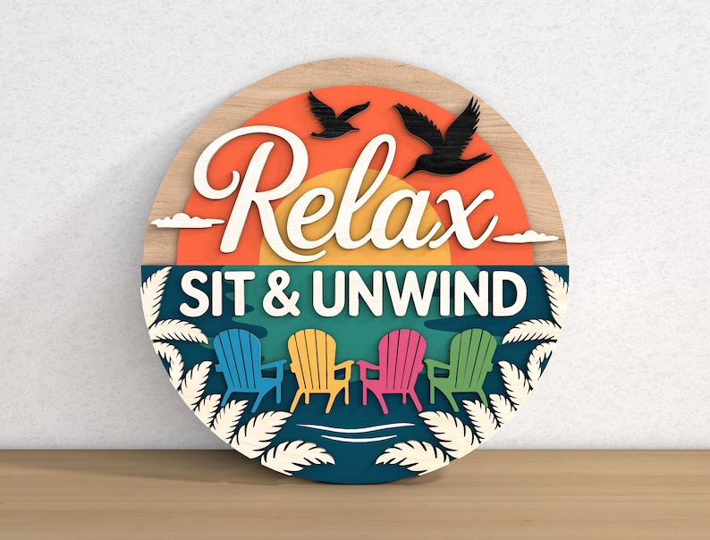 May include: A round wooden sign with the words "Relax SIT & UNWIND" in white script. The sign features a sunset, birds, and colorful Adirondack chairs. The sign is a decorative item.