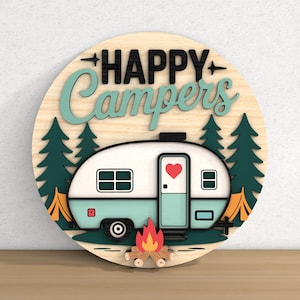 May include: A round wooden sign with the words "HAPPY Campers" in black and teal lettering. The sign features a teal and white camper with a red heart on the door, surrounded by green trees, a campfire, and an orange tent.